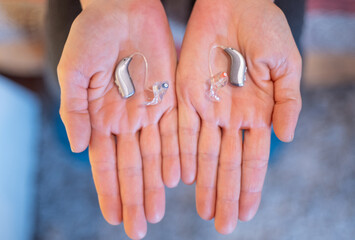 Showing modern hearing aids on both hands