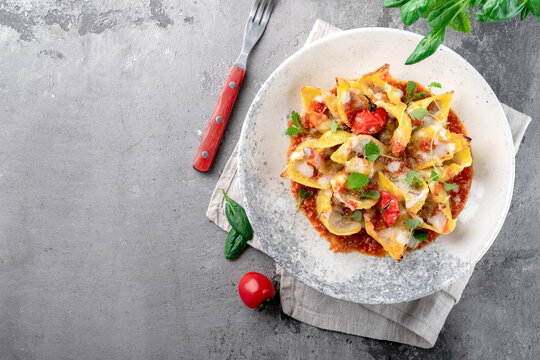 Pasta Conchiglionii filled with minced meat with tomatoes, bolognese sauce and Parmesan. An original Italian pasta dish served on a plate, top view and copy space