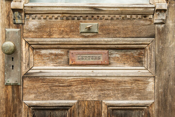 Antique door detail of mail slot (horizontal)  with the word "letters" in raised text on the flat of the slot.