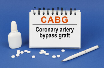 On a blue background, a pen, tablets and a notepad with the inscription - CABG Coronary artery...
