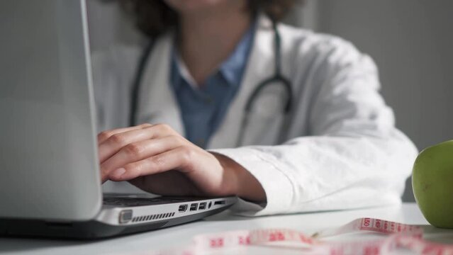 The doctor employee the hospital works on a laptop computer making out life insurance Registration of insurance paper for people who are afraid for their health life work with hands on laptop doctor a