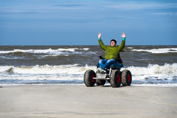 Mann im Strand-Rollstuhl, hebt die Arme vor Freude, Sankt-Peter-Ording, Schleswig-Hostein, Deutschland
