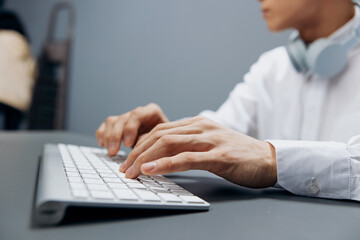 worker in headphones hands on keyboard office work close-up isolated background