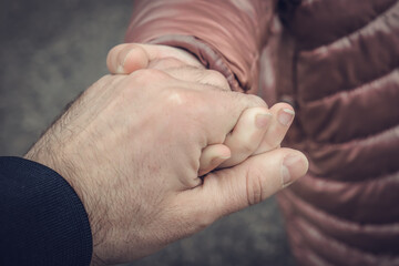 The father is holding his daughter's hand. Close-up shot