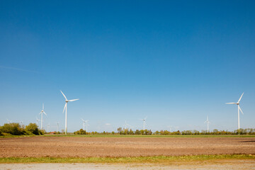 wind turbine in the field. wind turbine on sky. Large wind turbine next to a tree in spring. Wind turbine in summer. East Frisia in Germany