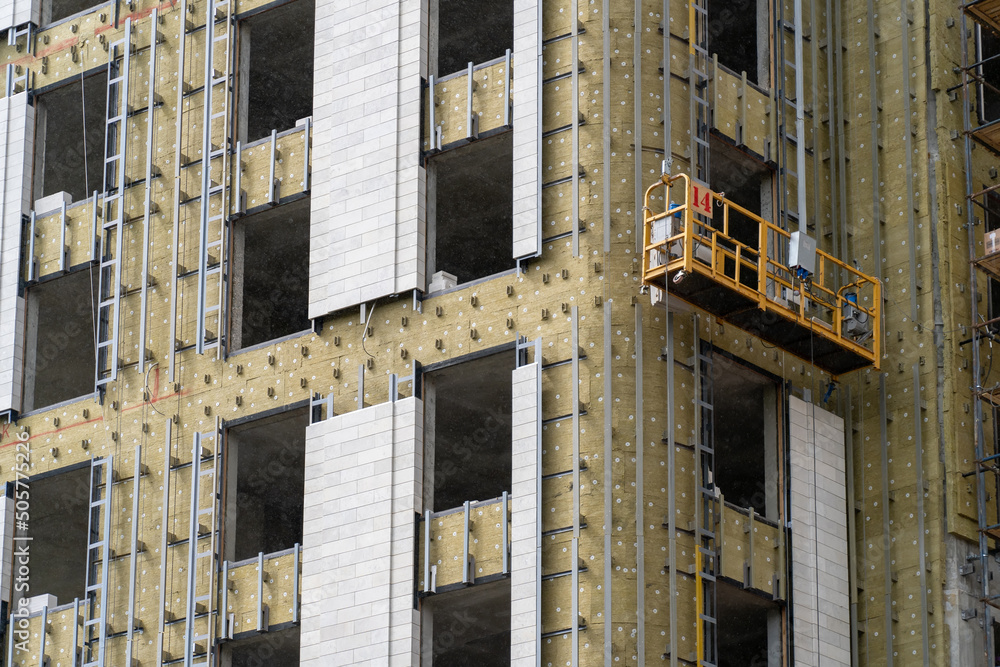 Poster installation of external wall thermal insulation with rock wool. monolithic concrete frame of apartm