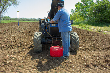 Picture of a farmer who in an agricultural field sucks up a diesel hose from a tractor. Reference to the excessive cost of fuel in the agricultural sector