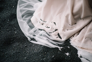 Hemline of wedding dress with basalt gravel on skirt on Black Sand beach in Vic, Iceland
