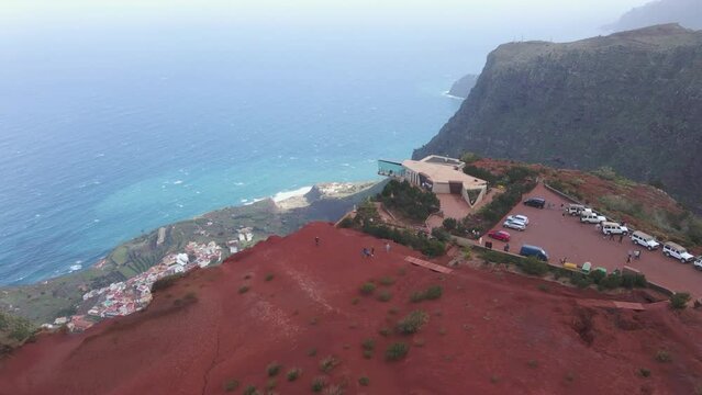 Aerial view of stunning viewpoint Mirador de Abrante with glass observation balcony above Agulo village in La Gomera island. Restaurant on red clay