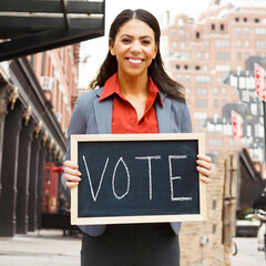 A woman holding a sign that says VOTE.