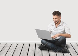Happy Guy With Laptop Sitting On Floor  Cheerful Man Using PC Computer and Relaxing