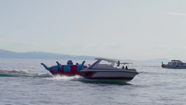 Follow shot of people enjoying the inflatable boat attraction