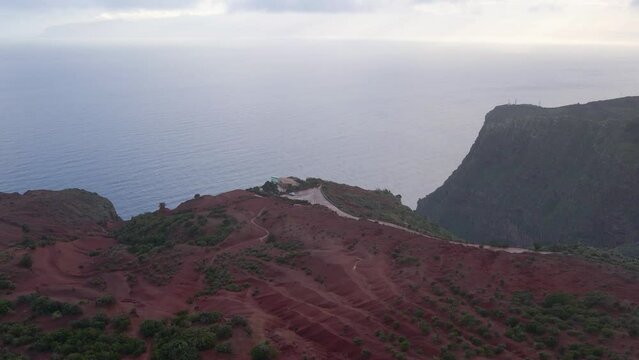 Aerial view of stunning viewpoint Mirador de Abrante with glass observation balcony above Agulo village in La Gomera island at sunrise. Restaurant on red clay