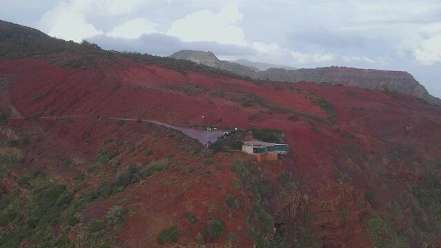 Aerial view of stunning viewpoint Mirador de Abrante with glass observation balcony above Agulo village in La Gomera island at sunrise. Restaurant on red clay