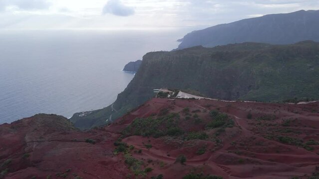 Aerial view of stunning viewpoint Mirador de Abrante with glass observation balcony above Agulo village in La Gomera island at sunrise. Restaurant on red clay