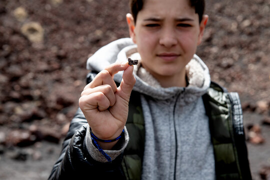 Italy, Sicily, Boy holding rock from Etna volcano