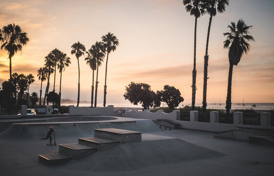 Boy, on push scooter in skatepark at sunset