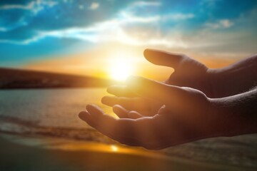 Fototapeta na wymiar Silhouette human hands open palm up on sunset beach. Christian praying concept
