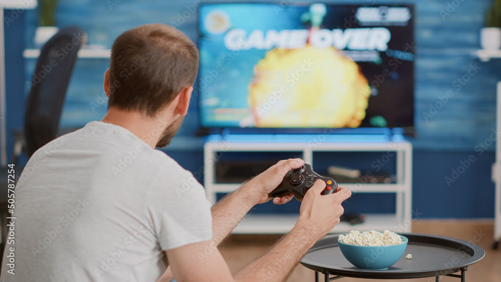 Poster closeup of man holding controller disappointed because losing online first person shooter game in fr
