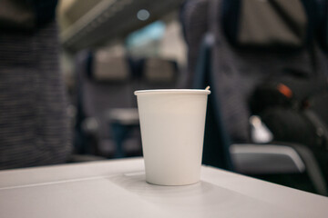 White disposable glass on the background of the interior of the train with a stick for coffee. High quality photo