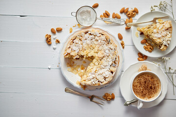 Whole delicious apple cake with almonds served on wooden table