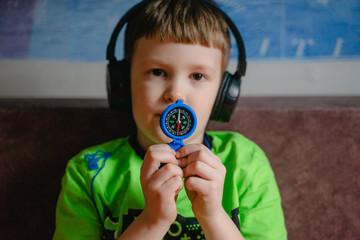 boy in headphones holding a blue compass in his hands