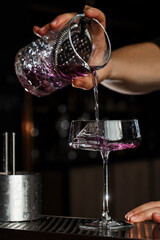 Bartender pouring Aviation, drink with gin, lemon juice,maraschino liqueur and violet cream liqueur...