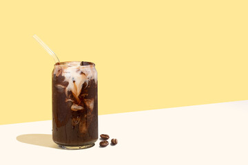 Coffee beans and cold coffee drink with glass straw on a yellow isometric diagonal projection...