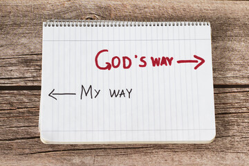 God's way, a handwritten text quote and arrows in a white notebook page placed on a wooden...