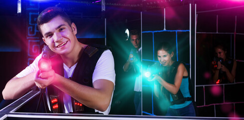 Fototapeta na wymiar positive guy holding laser pistol playing laser tag game with his friends