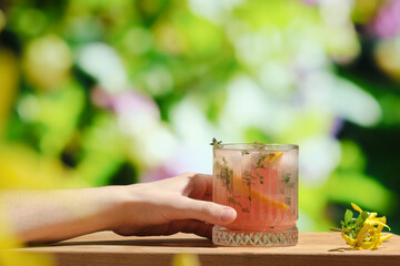Female hand holds glass of summer grapefruit cocktail.