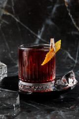 Crystal glass with bright cold alcoholic cocktail decorated with orange zest. Blurred background. Negroni cocktail.