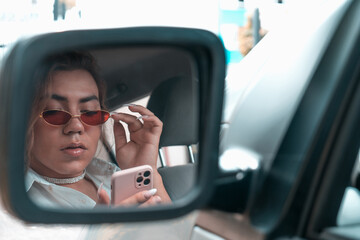 androgynous young looking your mobile at car in the rear view mirror