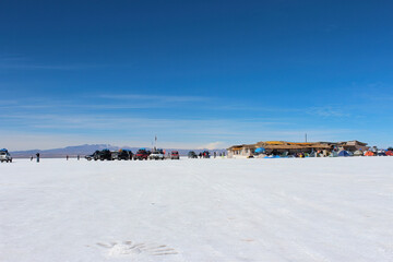 Fototapeta premium Salar de Uyuni, carros de transporte de turistas estacionados no horizonte branco .