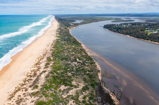 Aerial view of a river running along side a sandy beach