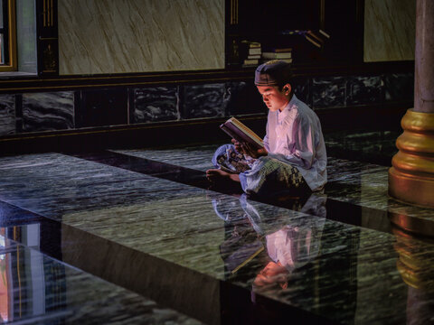 muslim student studying and reading Islam holy quran book in mosque