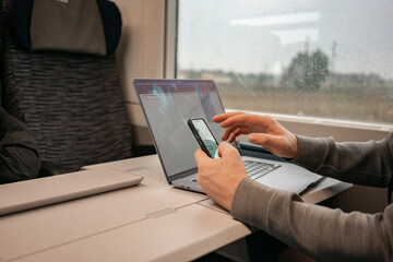 A man works online sitting on a train while traveling, remote work. Laptop and phone stand on the train table. High quality photo - 505797677