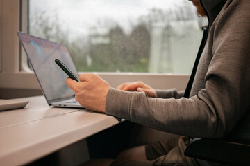 A male traveler works online on a European train while traveling by train. Unrecognizable man. High quality photo - 505797693