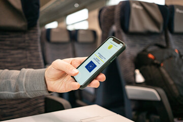 A man's hand holds a phone with a green pass italy on the train during a vaccination check. High quality photo