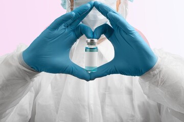 The shape of heart made from hands in gloves holding the covid vaccine shot