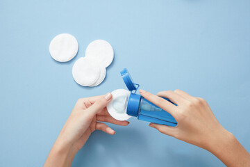 Topview of hand model using makeup remover on cotton pad in blue background for cosmetic advertising  © Tuan  Nguyen 