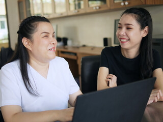 Happy Asian women co-workers in workplace including person with blindness disability using laptop...