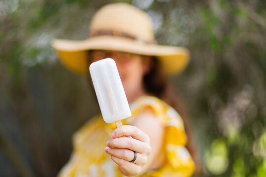 Woman holding out white ice block - cold treat for summer