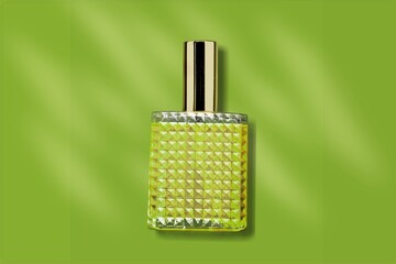 Bottle of perfume with spray on a green bokeh background. Natural  Clear glass.