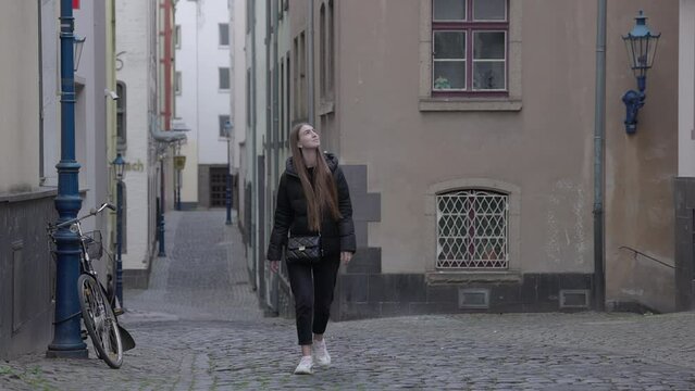 Young caucasian woman walking by old buildings in Europe. Female tourist strolling along empty streets on sleepy morning. High quality 4k footage
