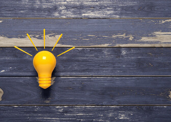 Orange color light bulb icon tips and tricks concept. On the dark blue painted wooden wall. Horizontal composition. Isolated with clipping path.