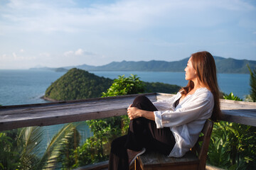 Portrait image of a young asian woman sitting and looking at a beautiful sea view from resort...