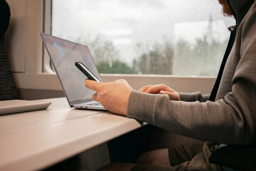 A man works at a table on a train. Remote work, traveling around Europe by train. Train interior....