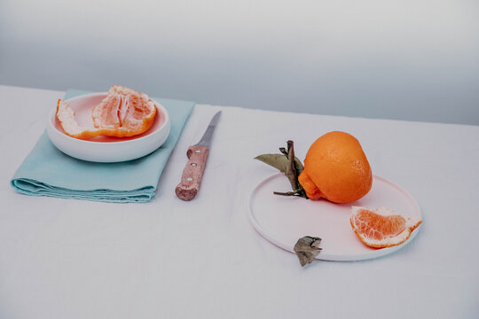still life with fruit on the dining table. mineola on a white dining table. mineola with leaves and scrapings. still life with orange citrus fruits