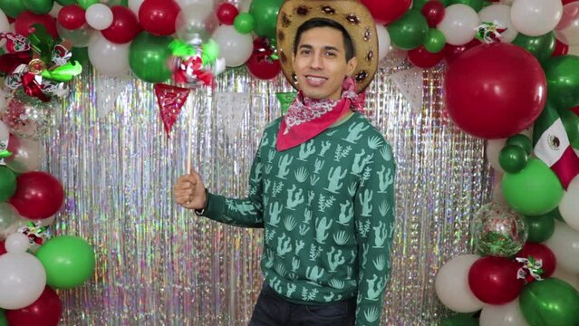 Mexican young man celebrating and blowing pinwheel at 5 de mayo